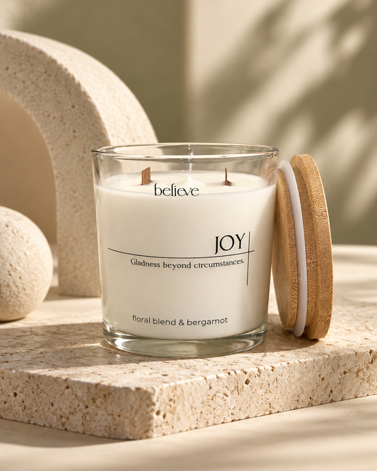 JOY candle in a clear glass jar with its wooden lid resting beside it