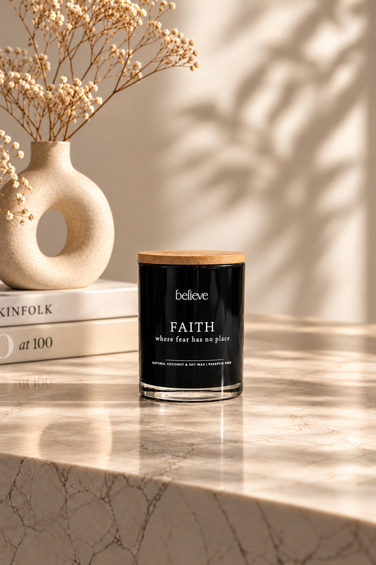 FAITH candle with wooden lid on a marble ledge beneath soft leaf shadows